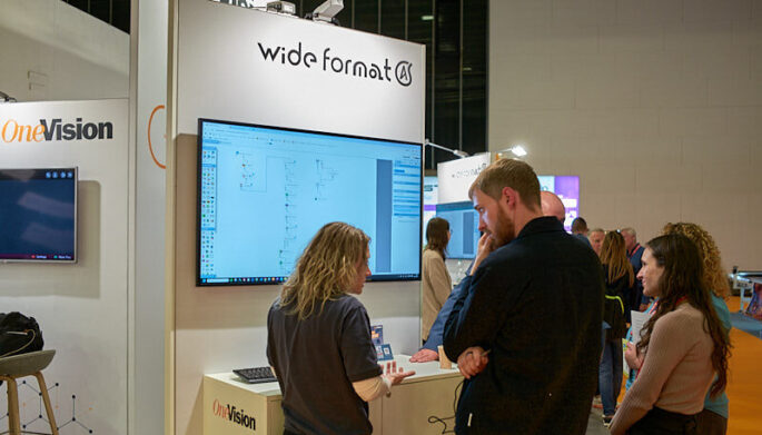 Customer looks at OneVision wide format software on screen at print expo