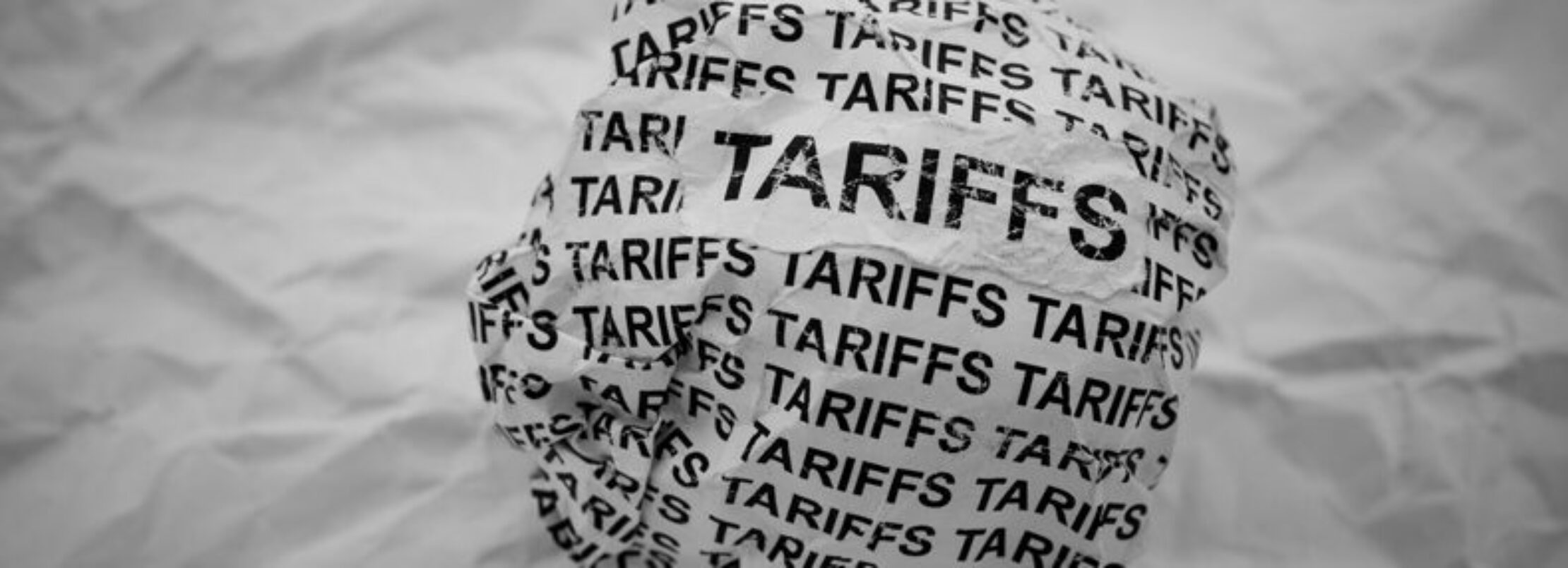 Crumpled ball of paper with word tariffs repeated across it